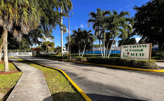 Entrance view of the Gardens of Kendall South with a sign and surrounding greenery.