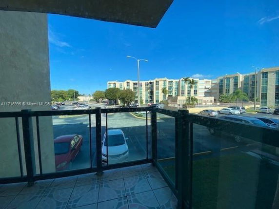 View from a balcony showing a parking area and apartment buildings in the distance.
