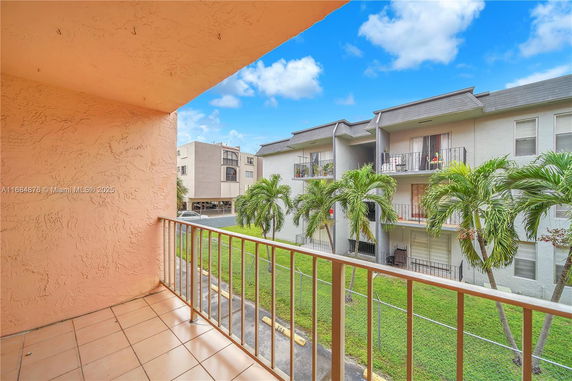 View from a balcony showing nearby multi-story residential buildings and palm trees.