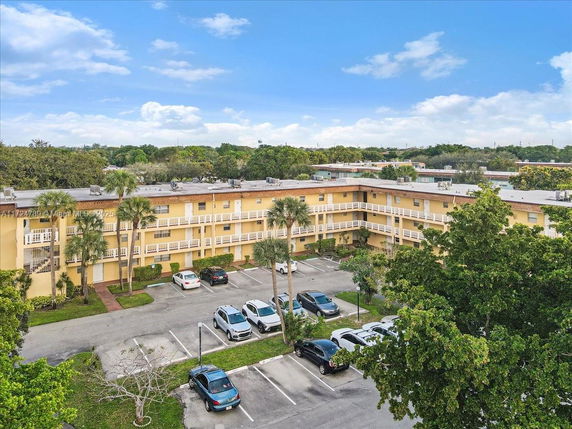 View of a multi-story residential building with parking area and trees around.
