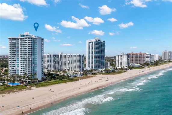 Aerial view of beachfront high-rise buildings next to a sandy beach and ocean.