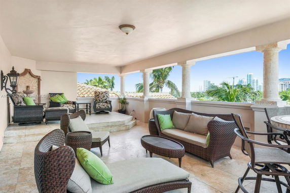 Covered rooftop patio with wicker furniture and city skyline views.