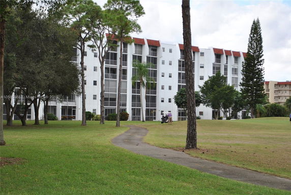 Front view of a multi-story residential building with balconies and red roof accents.