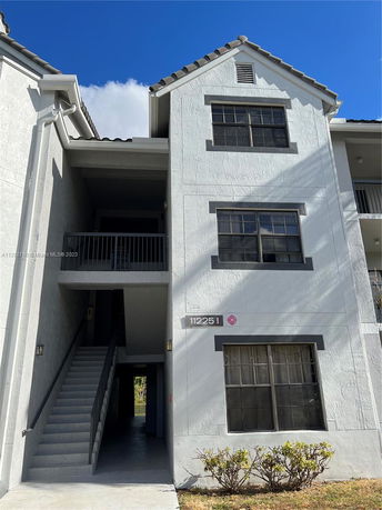 Front view of a multi-story residential building with an exterior staircase.