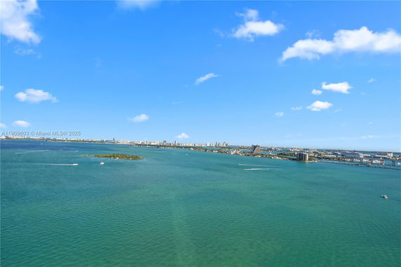 Wide angle view of the ocean and distant cityscape under a blue sky.