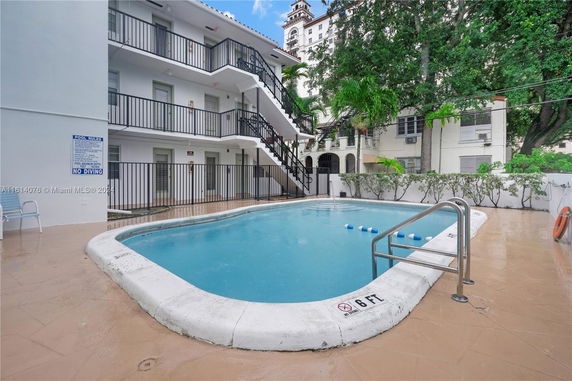 View of an outdoor swimming pool near a multi-story building with balconies.