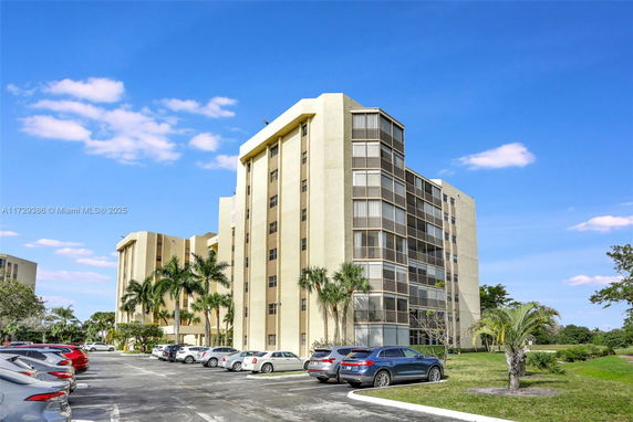 Front view of a multi-story apartment building with parking area.