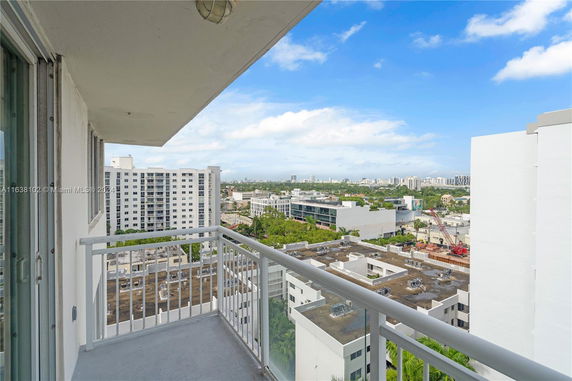 View from a building balcony overlooking cityscape with residential and commercial buildings.