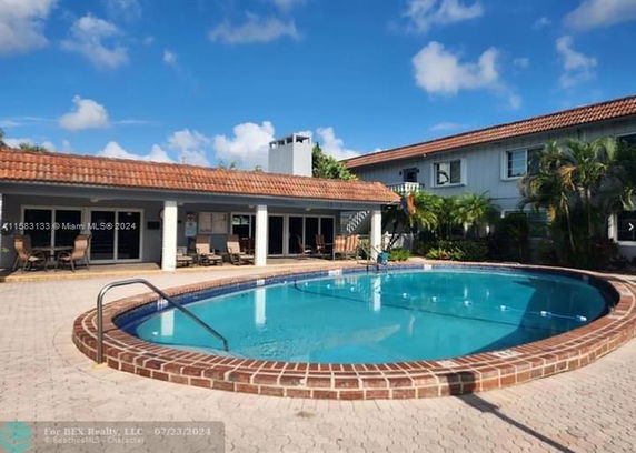 Outdoor swimming pool beside a two-story house with tiled roofs.