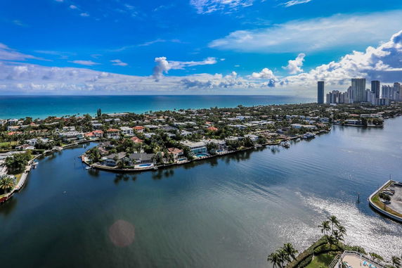 Panoramic view of waterfront homes and distant city skyline along the coastline.