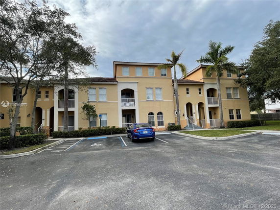 Front view of a multi-story residential building with parking spaces.
