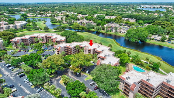 Aerial view of a residential complex with multiple buildings surrounded by greenery and water bodies.