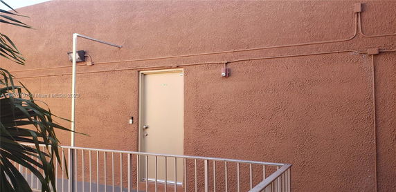 View of an external wall with a door and railing.