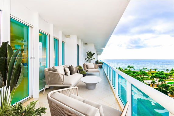Balcony view with seating area overlooking the ocean.