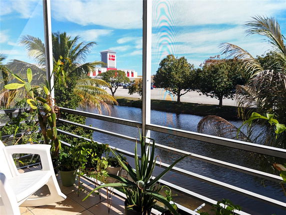 View from a balcony showing a waterway, palm trees, and a distant building.