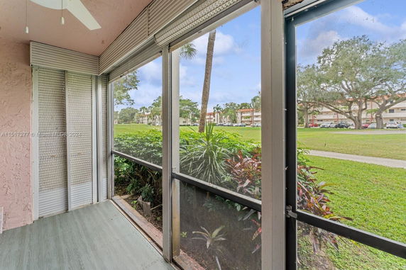 Screened-in porch view overlooking grassy area and distant buildings.