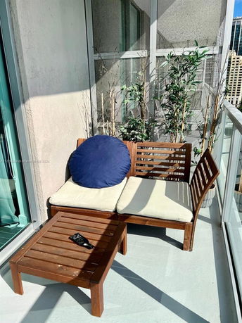 Outdoor balcony area with wooden furniture and potted plants.