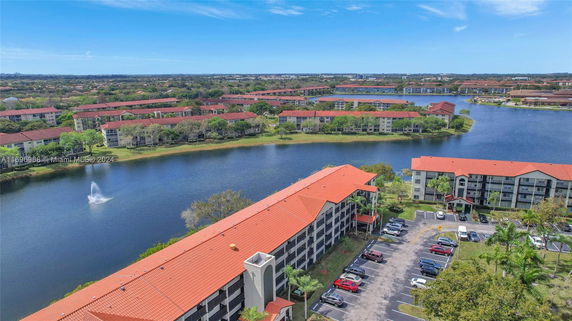 Panoramic view of a residential area with buildings near a lake and a fountain.