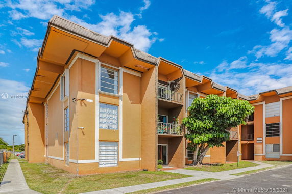 Front view of a multi-story apartment building with balconies and large windows.