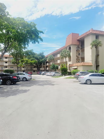 Outdoor parking area in front of a multi-story building with a tiled roof.