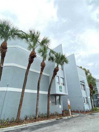 Front view of a multi-story building with palm trees.