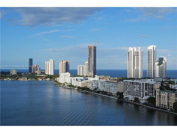 Panoramic view of high-rise buildings along a waterfront, with the ocean in the background.