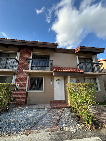 Front view of a two-story townhouse with balconies and a white door.