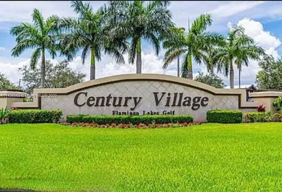 Signage of Century Village with palm trees in the background.
