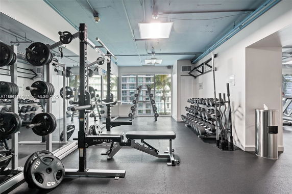 Interior view of a gym with exercise equipment, weights, and benches.
