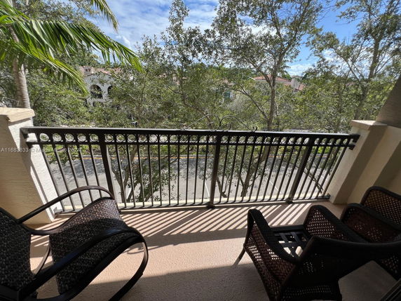 View from a balcony with chairs, showing trees and nearby buildings.