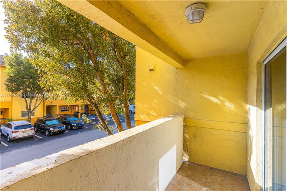Balcony view showing parked cars and neighboring buildings.