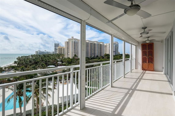 Balcony view overlooking tall residential buildings, beach, and ocean.