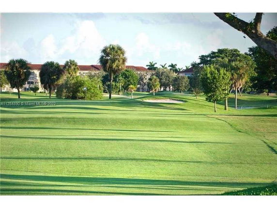 View of a golf course with trees and distant buildings.