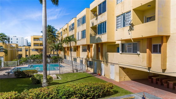 View of a multi-story building with a swimming pool in the courtyard.