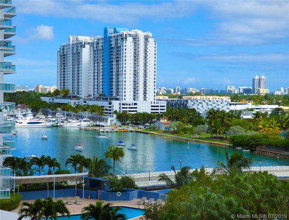 View of high-rise buildings and a marina with boats on a waterfront.