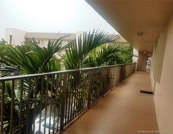View of a building walkway with palm trees visible over the railing.