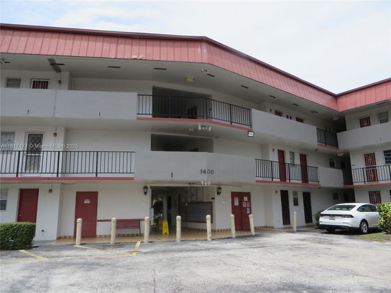 Front view of a two-story building with balconies and a parking area.