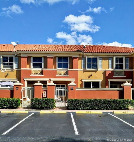 Front view of a two-story townhouse with a tiled roof and gated entrance.
