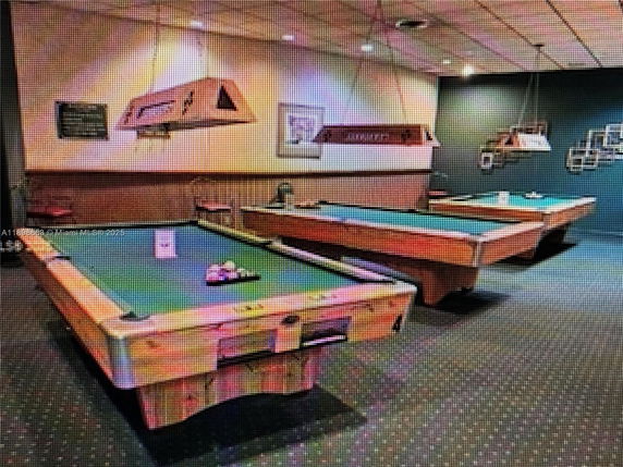 Room with multiple billiard tables and overhead lights.