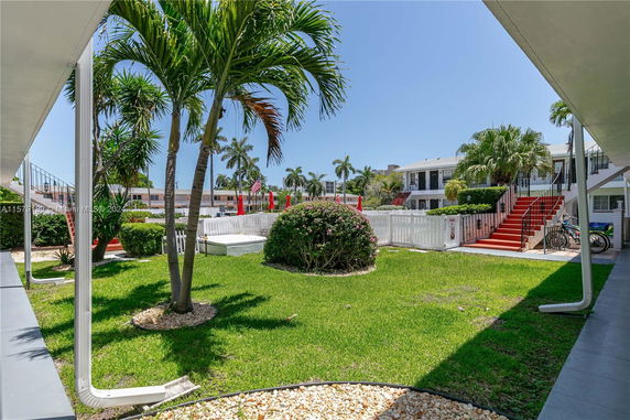 View of a garden area with surrounding buildings and palm trees.