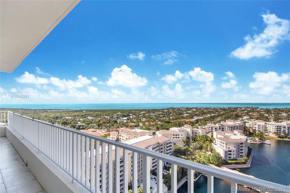 Panoramic view from a high floor balcony overlooking residential buildings and a distant ocean.