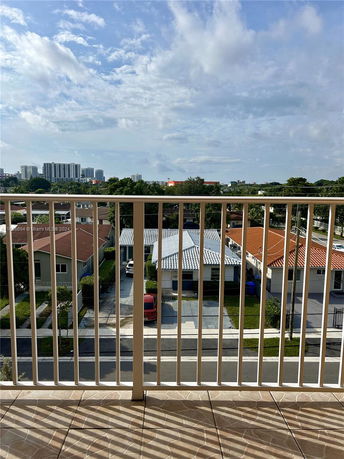 Panoramic view from a balcony overlooking residential houses and distant buildings.