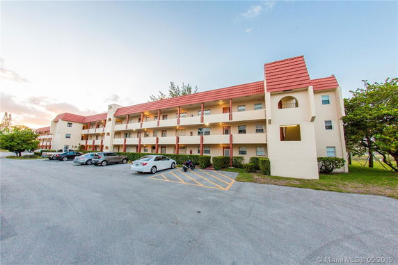 Front view of a multi-story apartment building with a red roof and balconies.