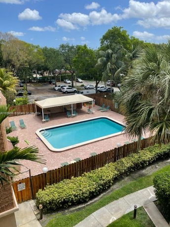 Outdoor swimming pool with surrounding fence and lounge chairs.