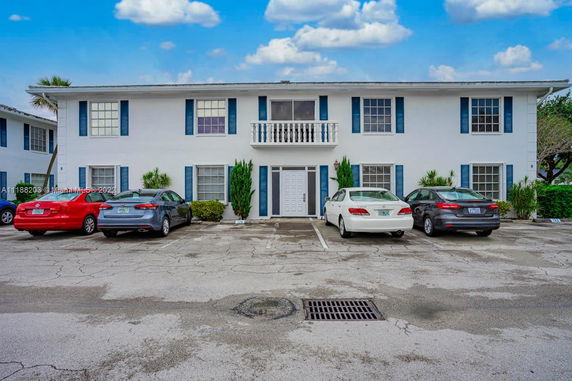 Front view of a two-story building with a central entrance and cars parked in front.