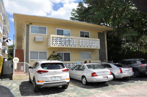 Front view of a two-story building with multiple cars parked in front.
