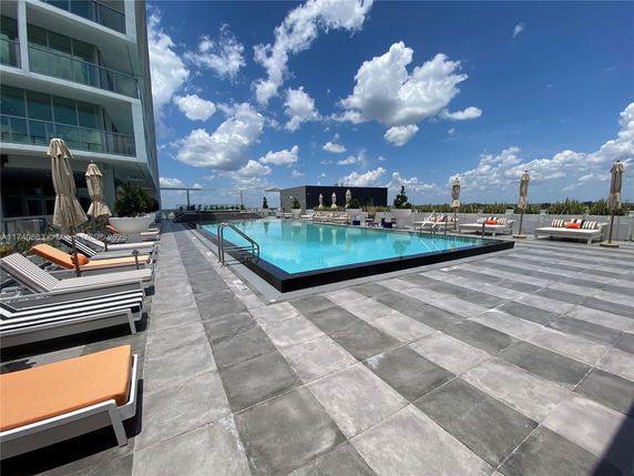 Rooftop swimming pool area with lounge chairs and umbrellas.
