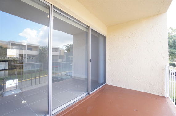 Balcony view with sliding glass doors and adjacent building in the background.