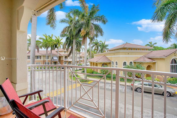 View from a balcony overlooking residential buildings and palm trees.