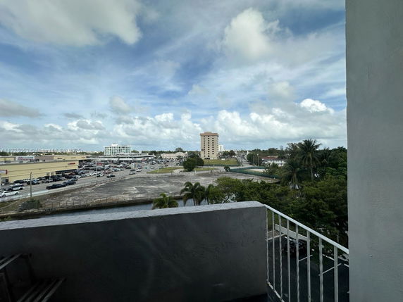 Panoramic view from a building overlooking a parking area and nearby commercial buildings.